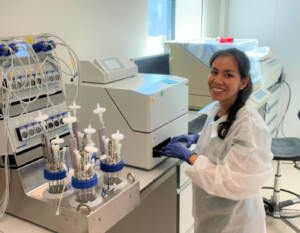 Photos of Ingrid Cardenas Rey in the laboratory of her university standing next to a diagnostics machine